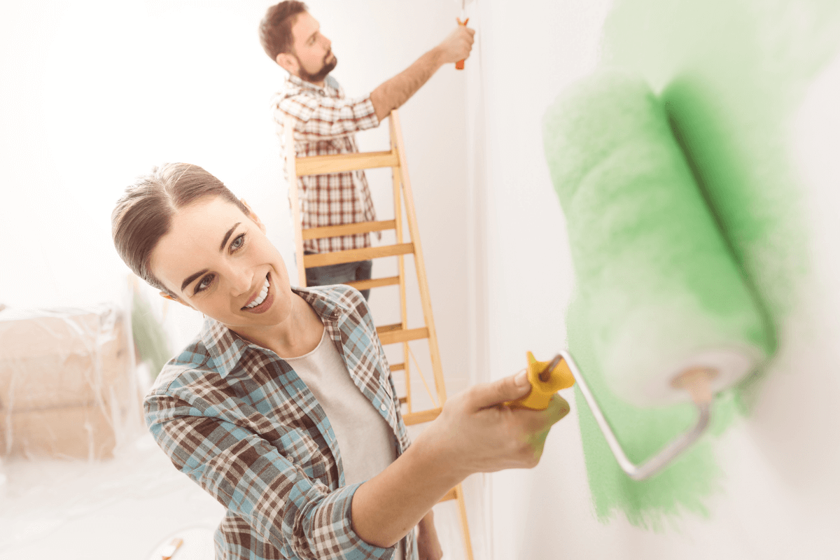 lady decorating the wall with green paint